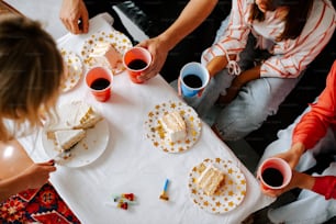 a group of people sitting around a table with cake and drinks