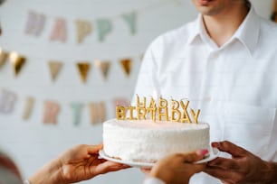 お誕生日おめでとうキャンドルが乗ったケーキを持っている人