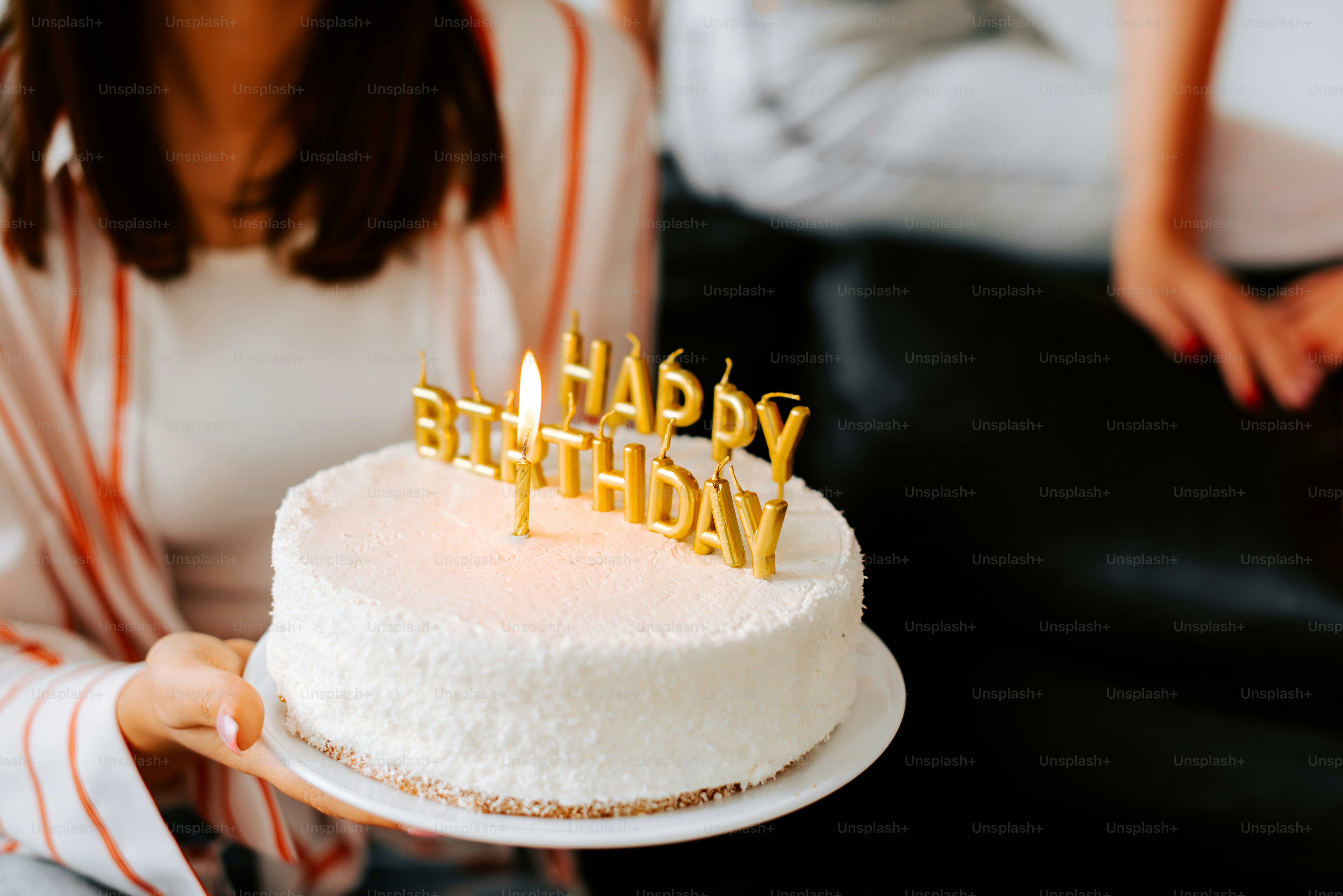 uma mulher segurando um bolo de aniversário com velas sobre ele