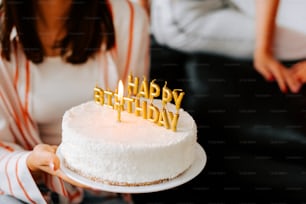 Una mujer sosteniendo un pastel de cumpleaños con velas