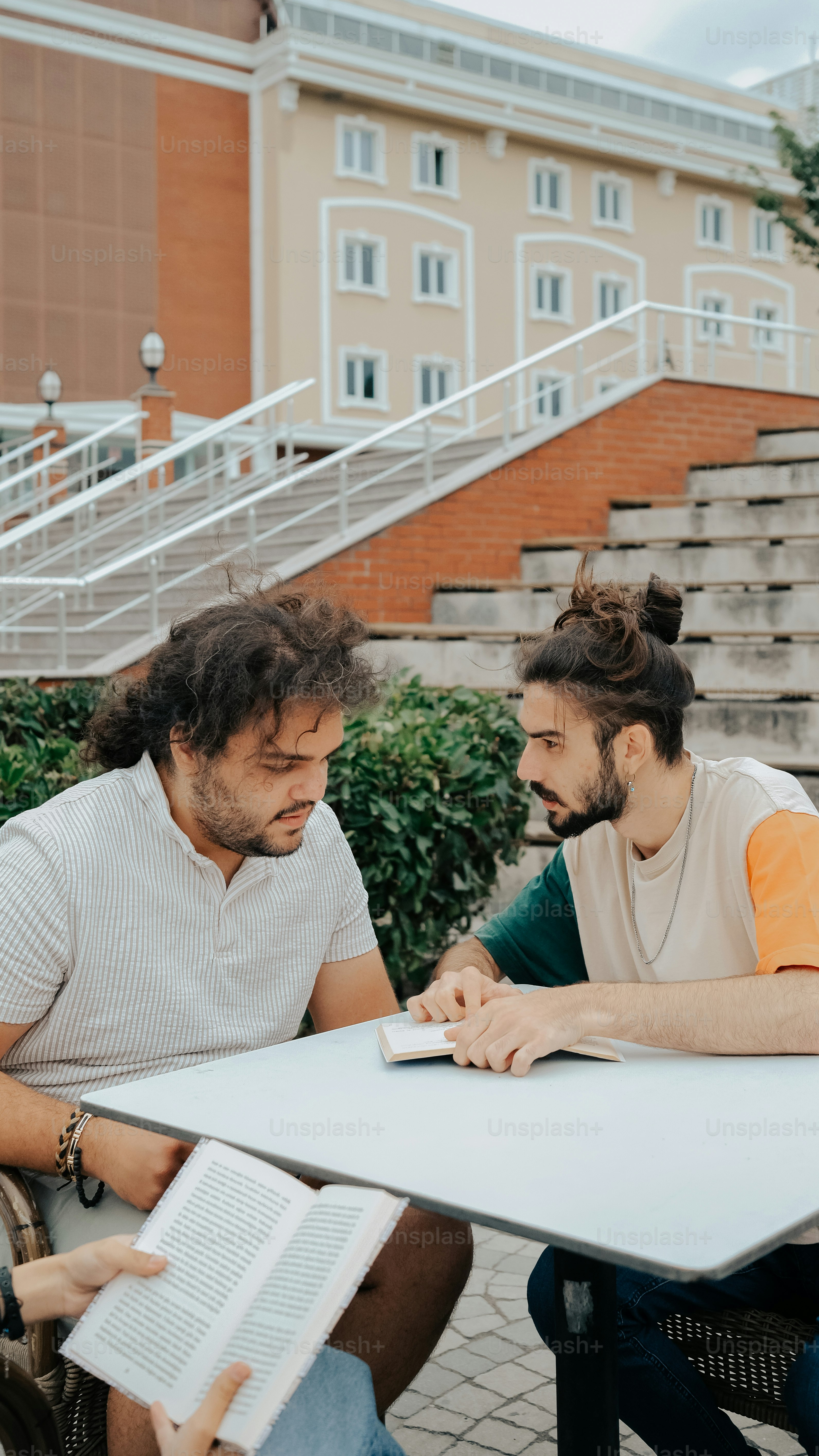 開いた本を持ってテーブルに座っている二人の男