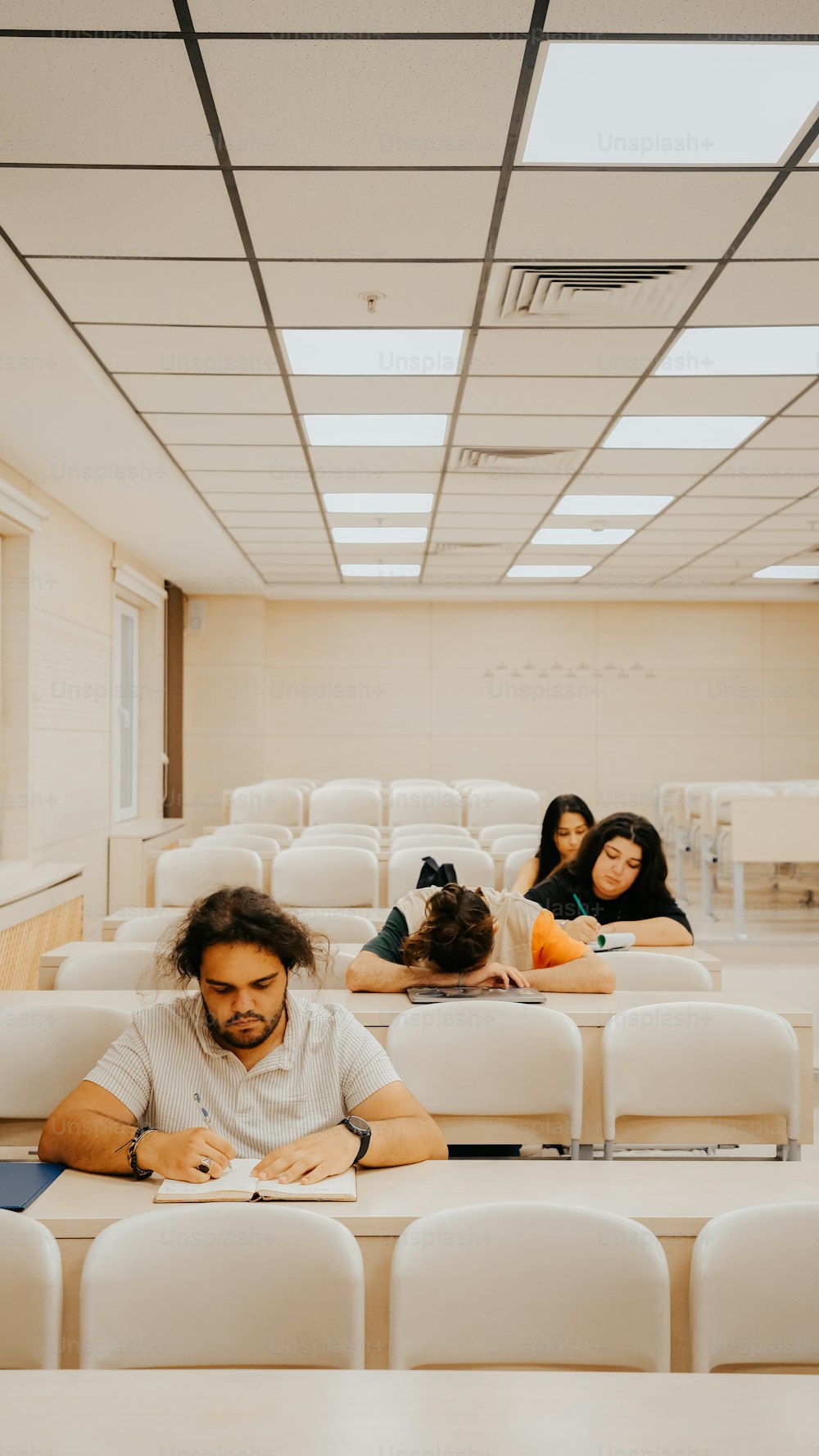 a group of people sitting in a room with white chairs