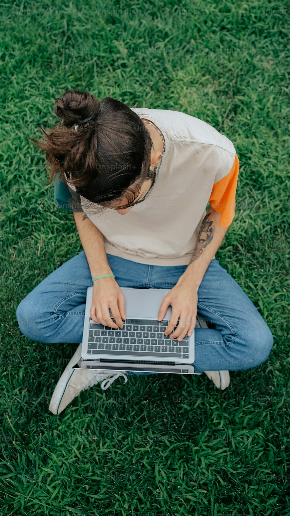 une personne assise dans l’herbe avec un ordinateur portable