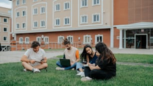 a group of people sitting on the grass with laptops