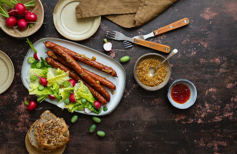 a plate of sausages, lettuce, radishes, bread and