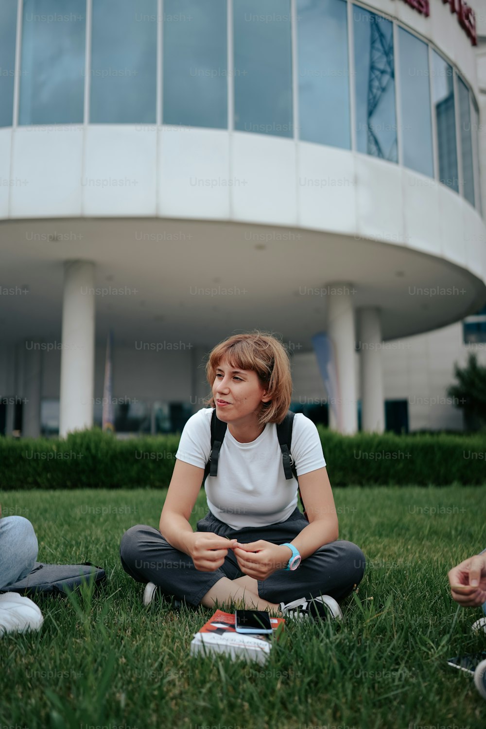 a woman sitting on the grass in front of a building
