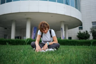 a woman sitting on the grass in front of a building