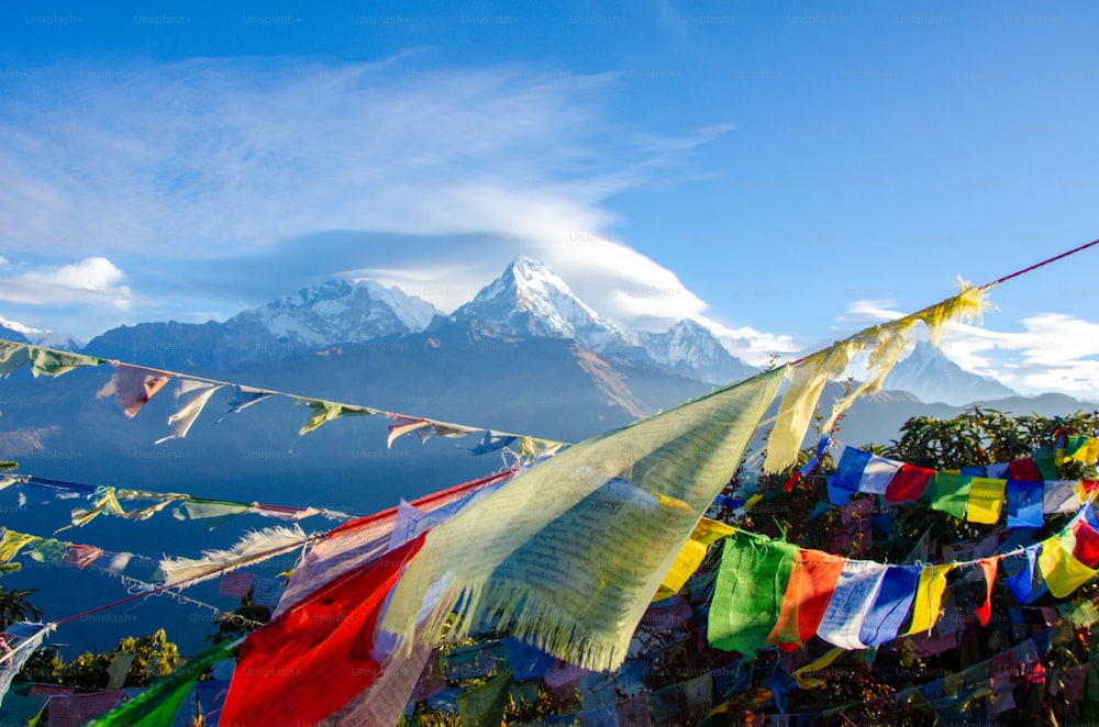 Um monte de bandeiras coloridas estão penduradas em frente a uma montanha