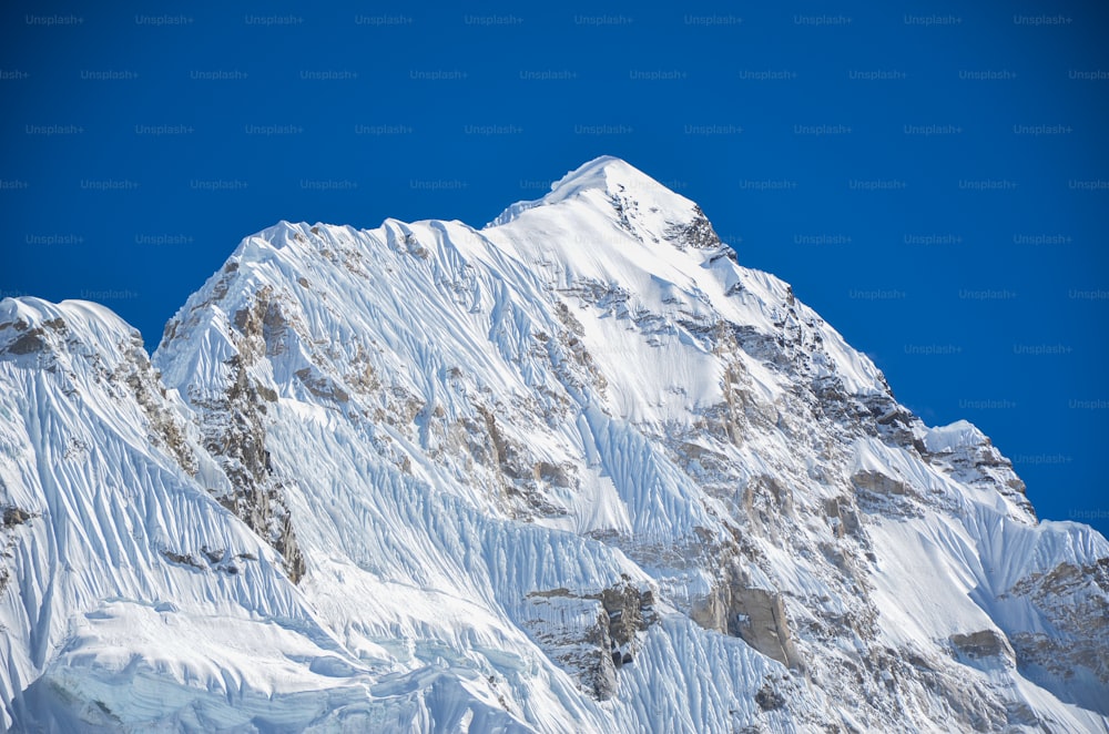 uma montanha coberta de neve com um céu azul ao fundo