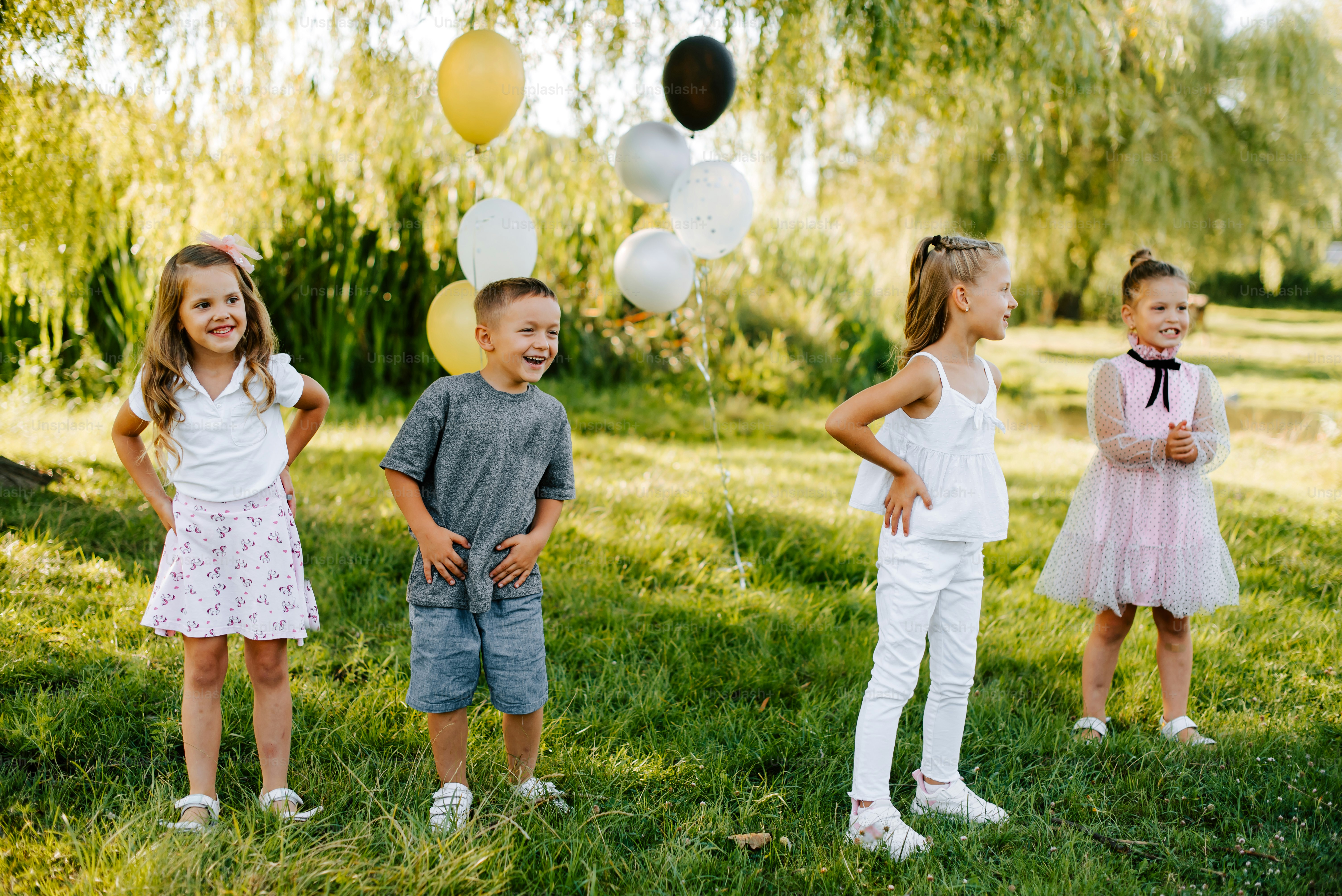 a group of young children standing on top of a lush green field