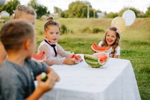 Eine Gruppe von Kindern sitzt an einem Tisch mit Wassermelonenscheiben