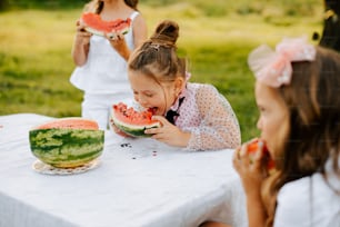 a little girl eating a watermelon slice at a table