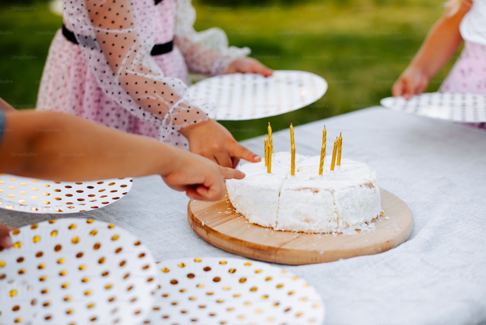 a group of children standing around a cake on top of a table