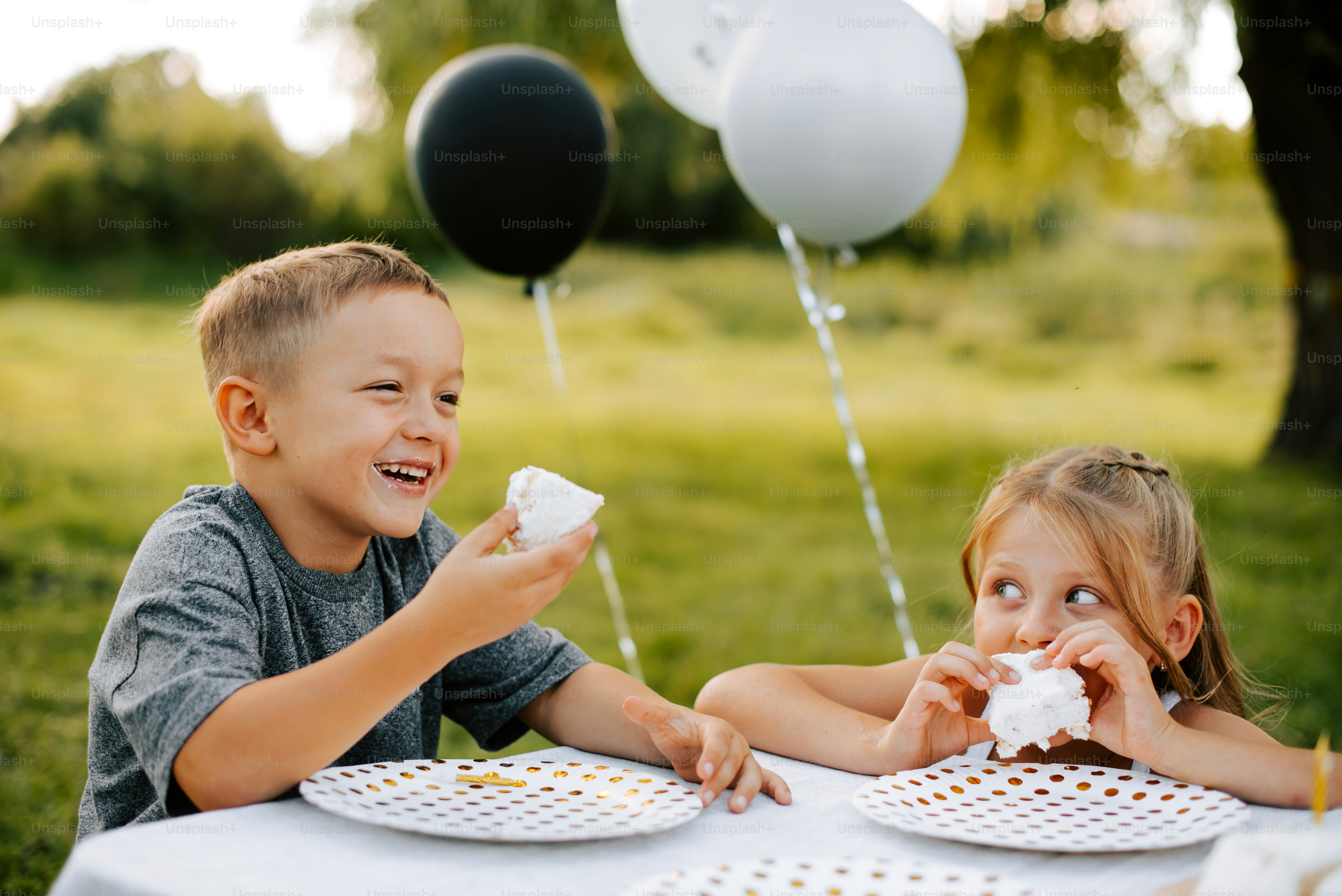 a couple of kids sitting at a table eating cake
