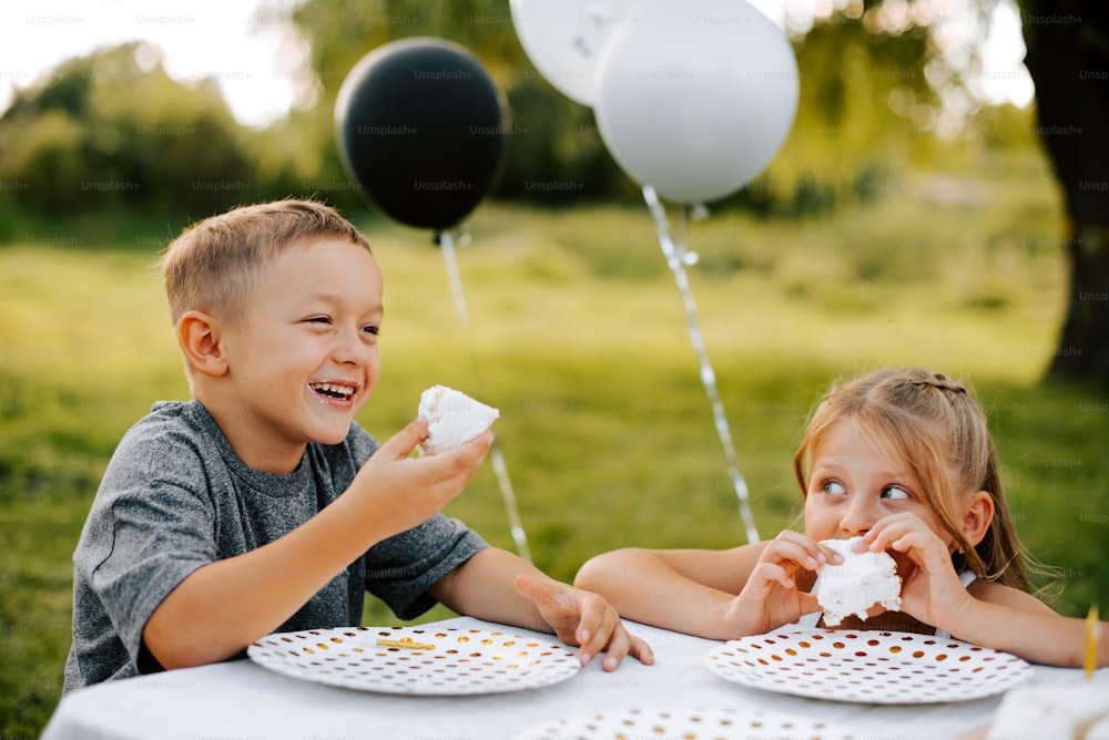 a couple of kids sitting at a table eating cake