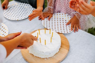 a group of people standing around a white cake
