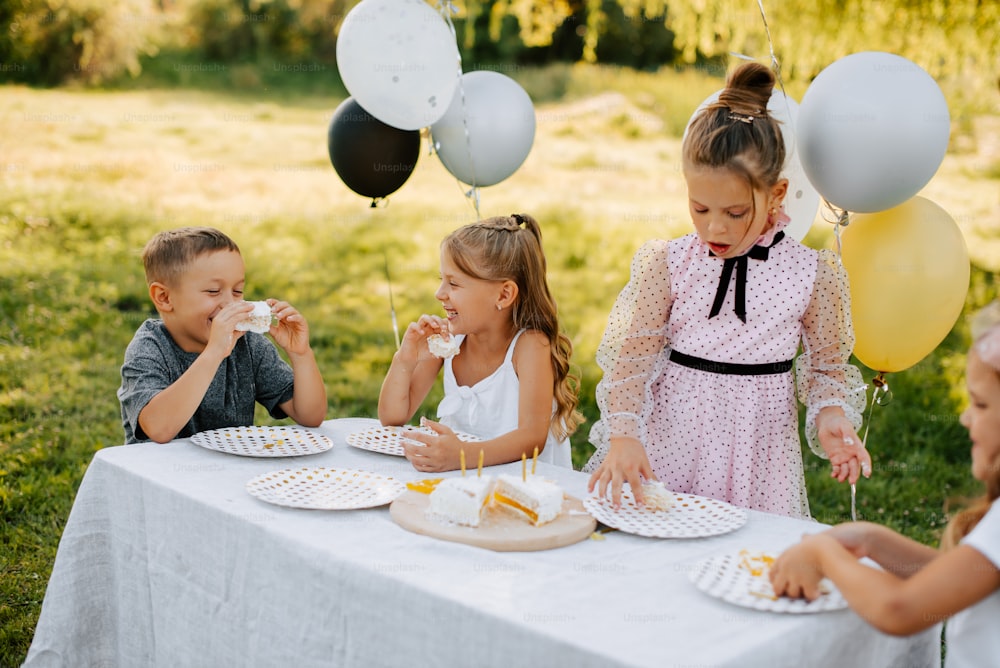 a group of children sitting at a table eating cake