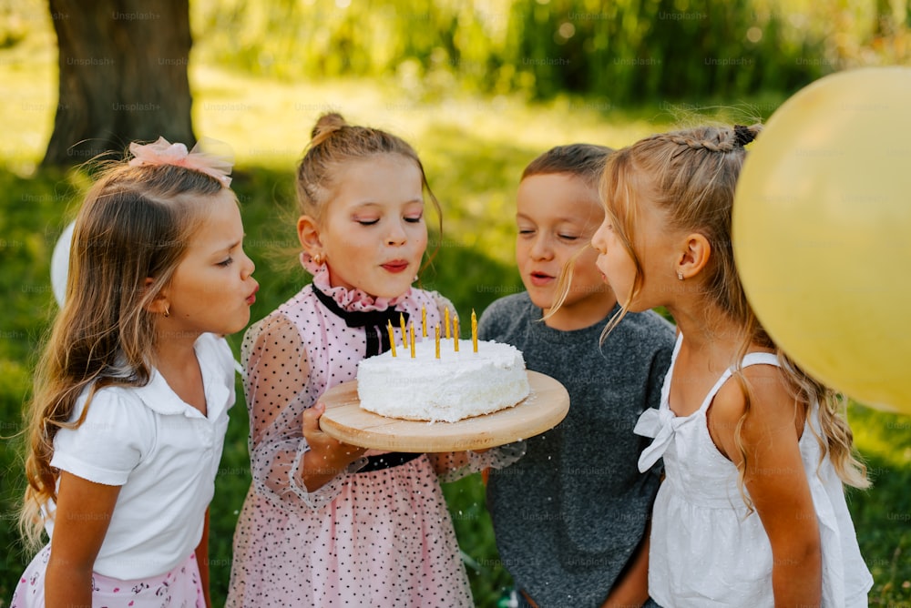 a group of young girls standing around a cake