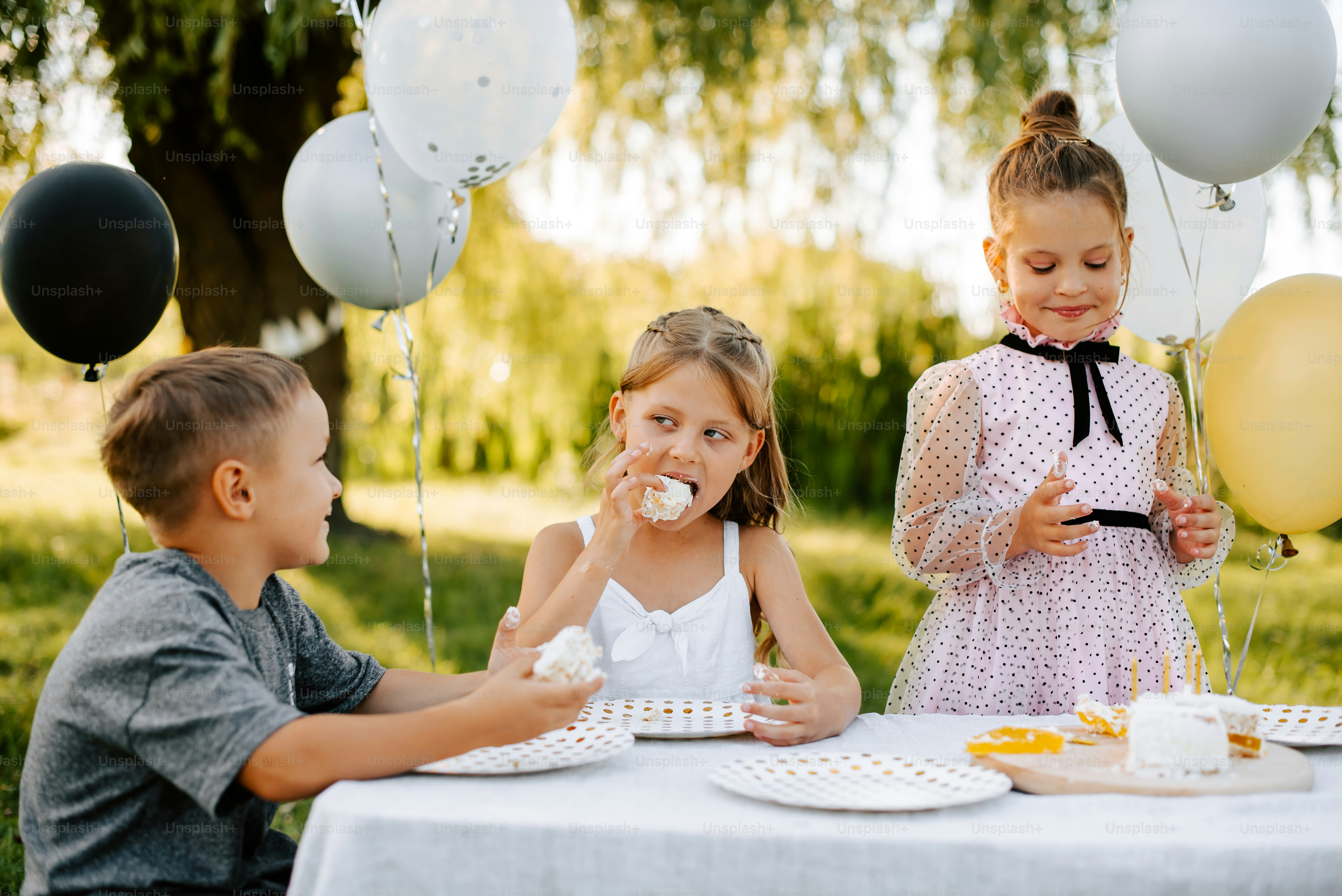 a group of children sitting at a table eating cake