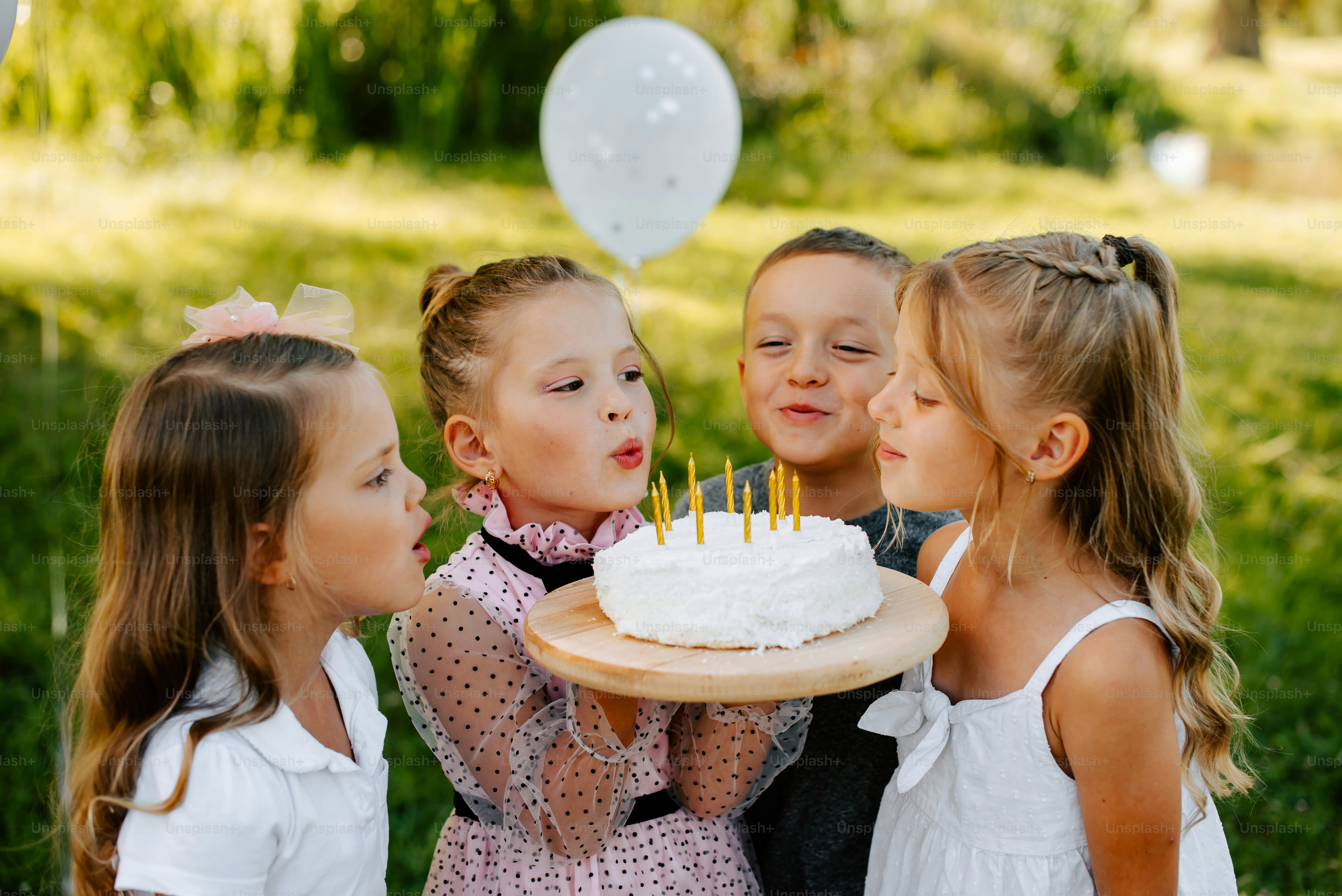 a group of young girls standing around a cake