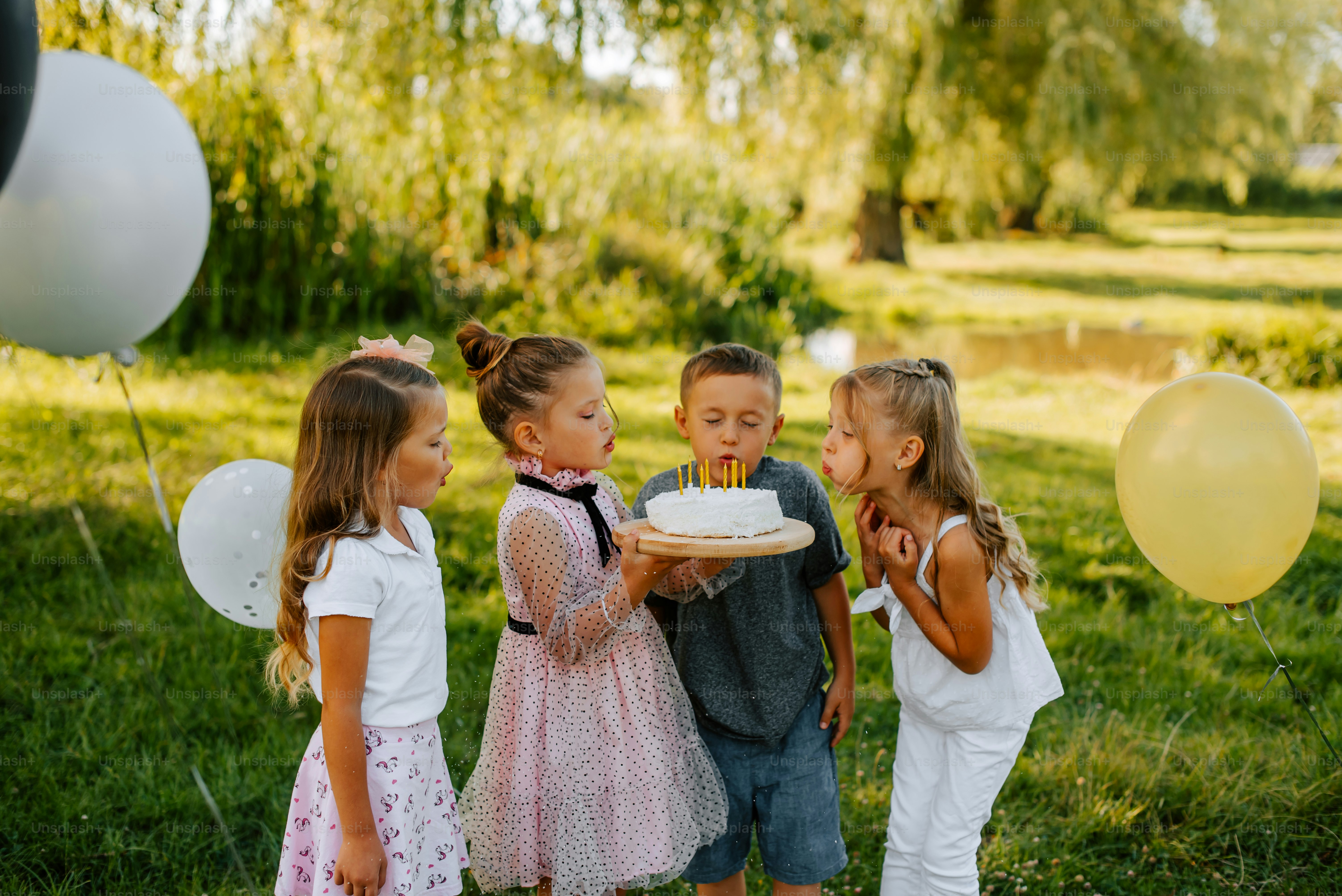 a group of young children standing around a cake
