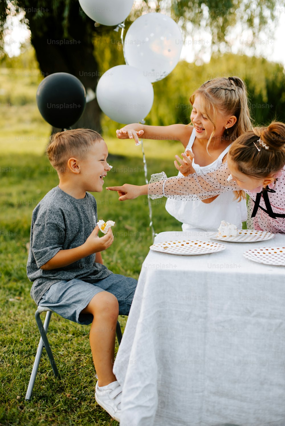 a group of children sitting at a table with balloons