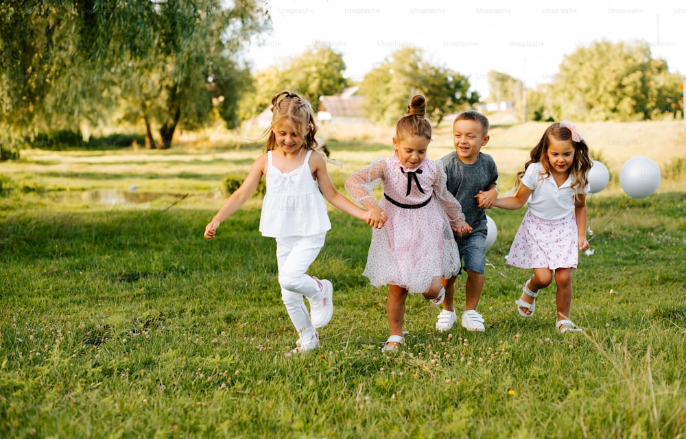 a group of young children running across a lush green field