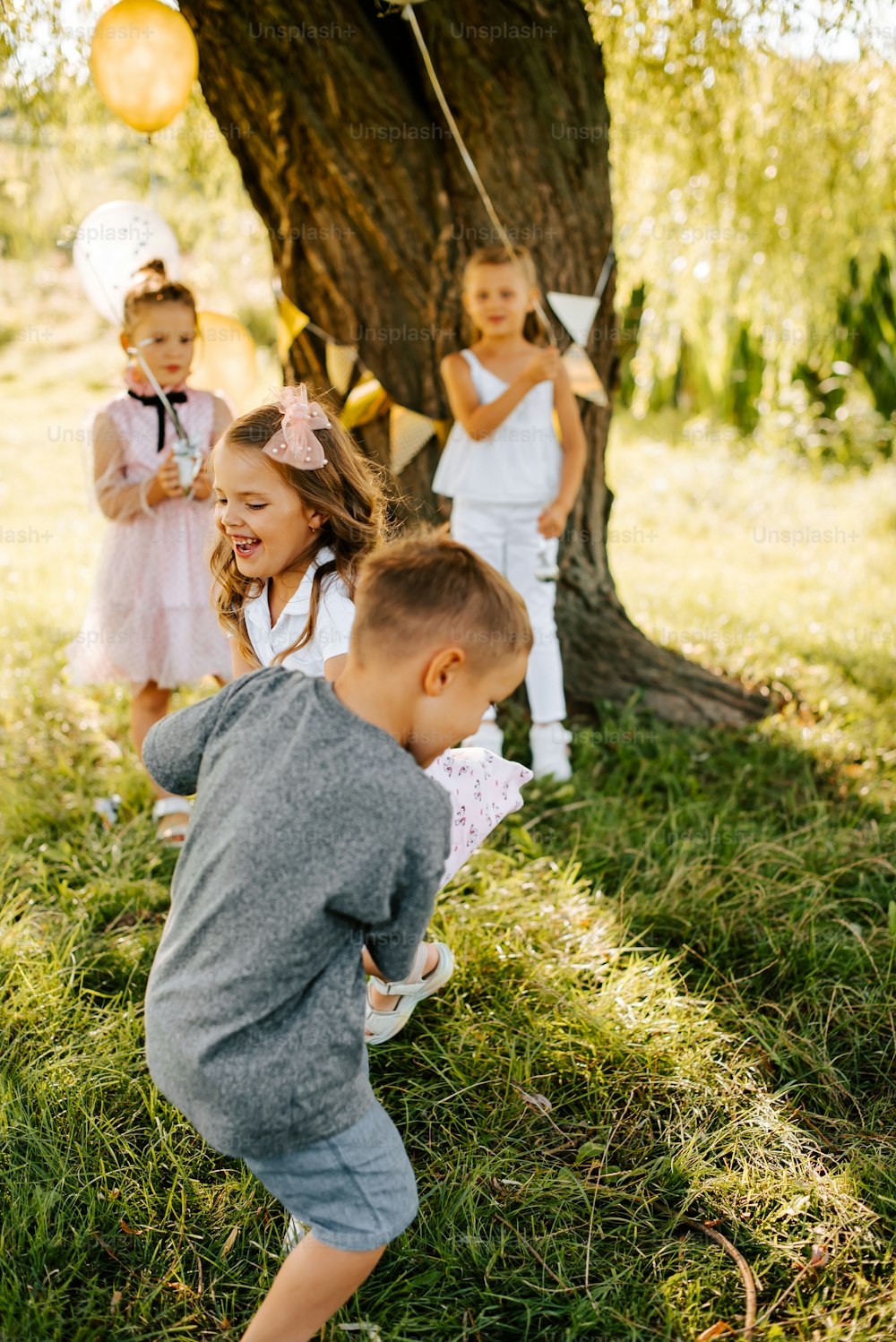 a group of young children standing next to a tree
