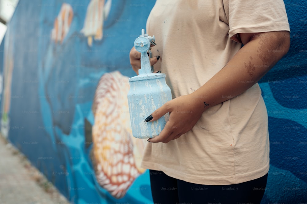 a woman holding a blue water bottle in front of a wall