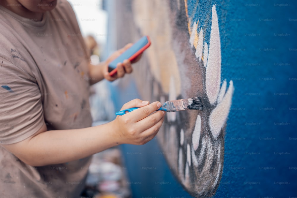 Un hombre está pintando una pared con pintura azul