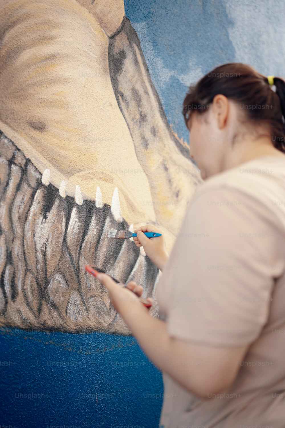 a woman is painting a picture of a dinosaur