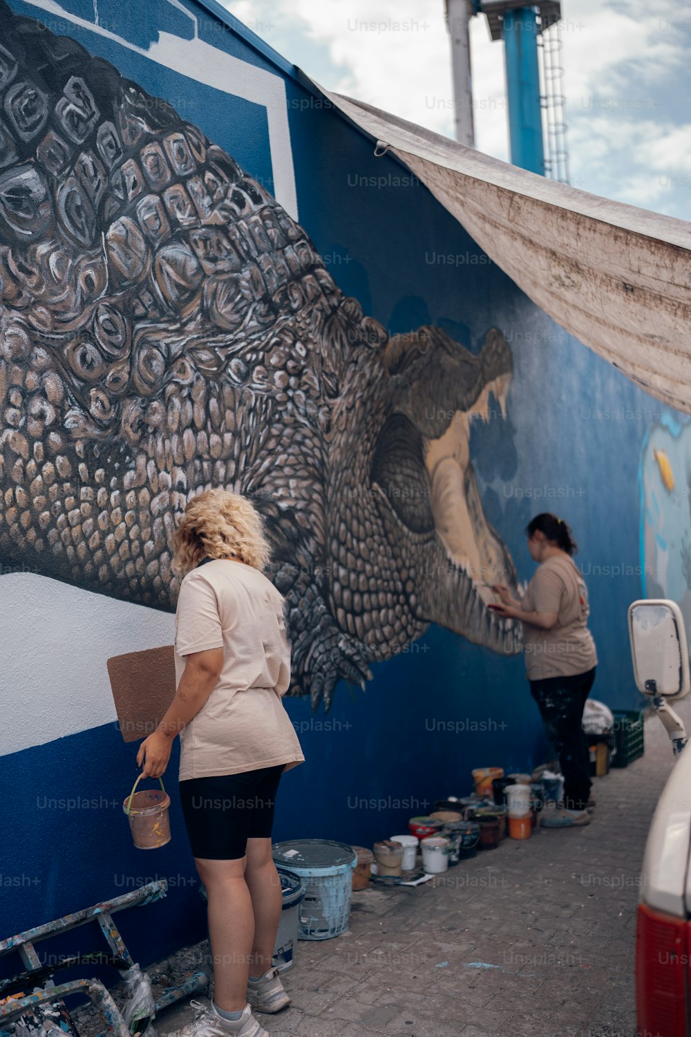 a woman painting a mural on the side of a building