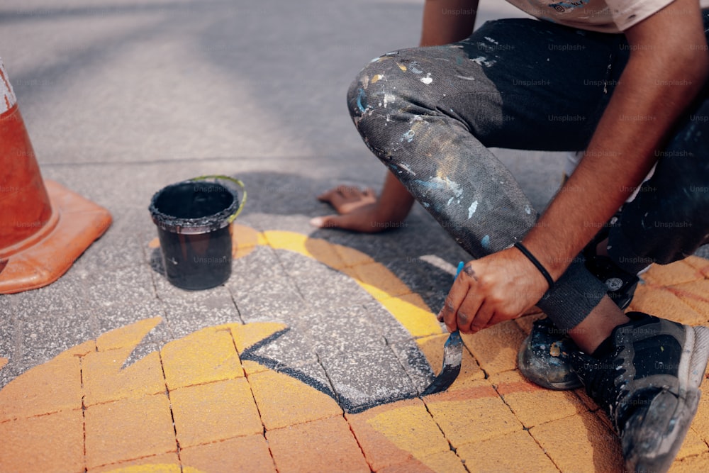 Un uomo sta dipingendo un marciapiede con un pennello