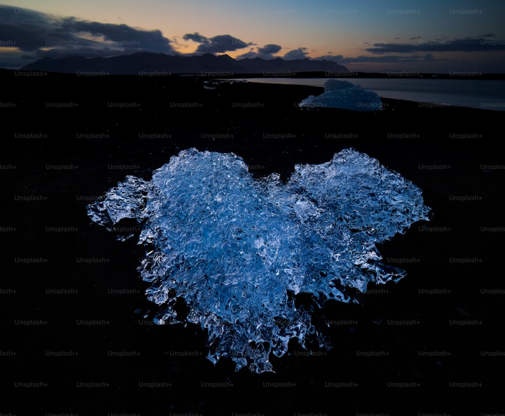 um pedaço de gelo em forma de coração sentado em cima de uma praia