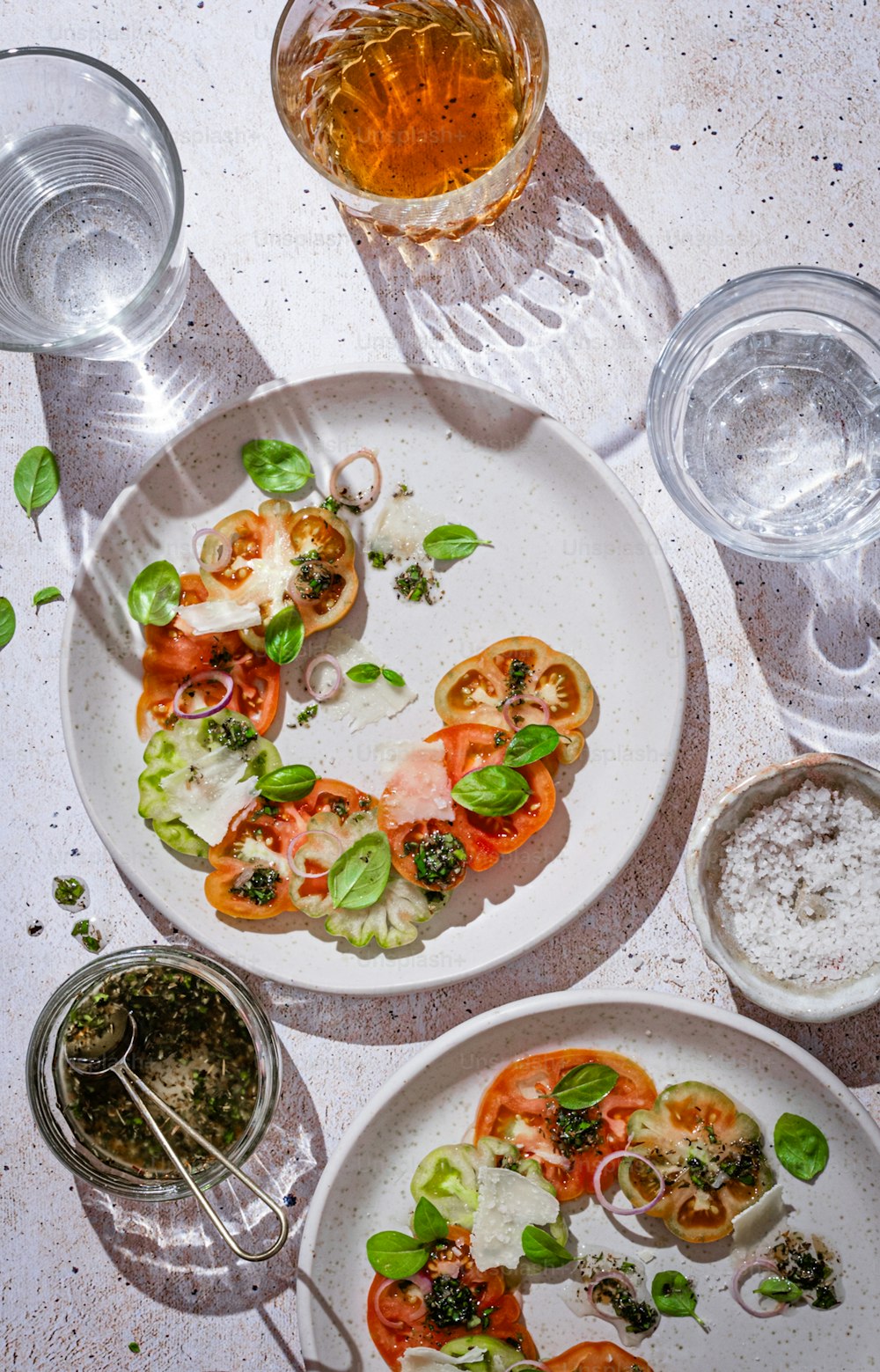 a white plate topped with sliced tomatoes next to a glass of beer