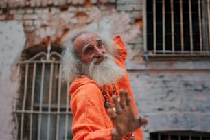 Un uomo con una lunga barba bianca e vestito arancione