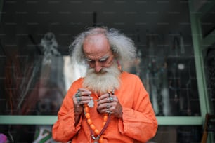 Ein Mann mit langem weißem Bart und orangefarbenem Hemd