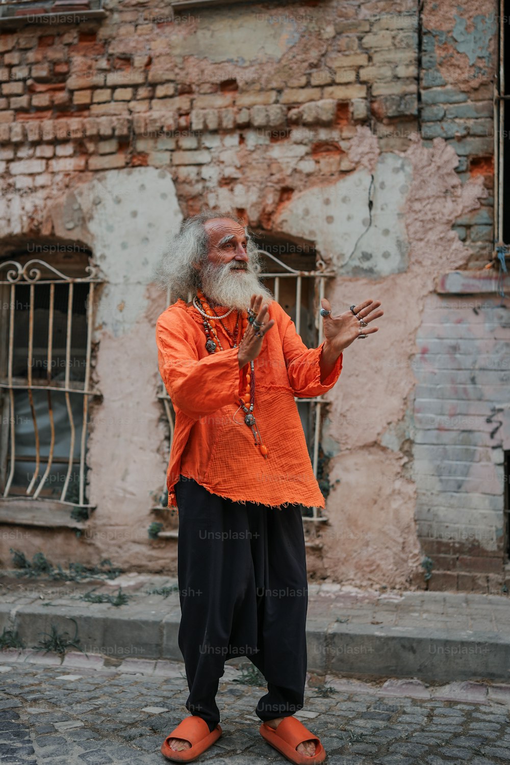 a man in an orange shirt standing in front of a building