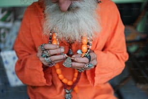 a man in an orange outfit holding beads