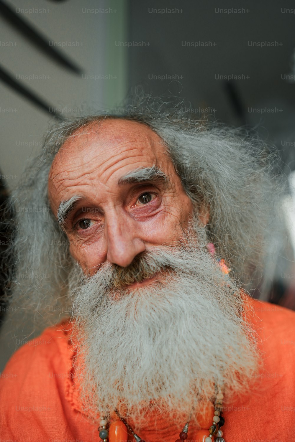 um velho de barba comprida e camisa laranja