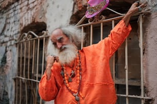 Un anciano con barba y camisa naranja