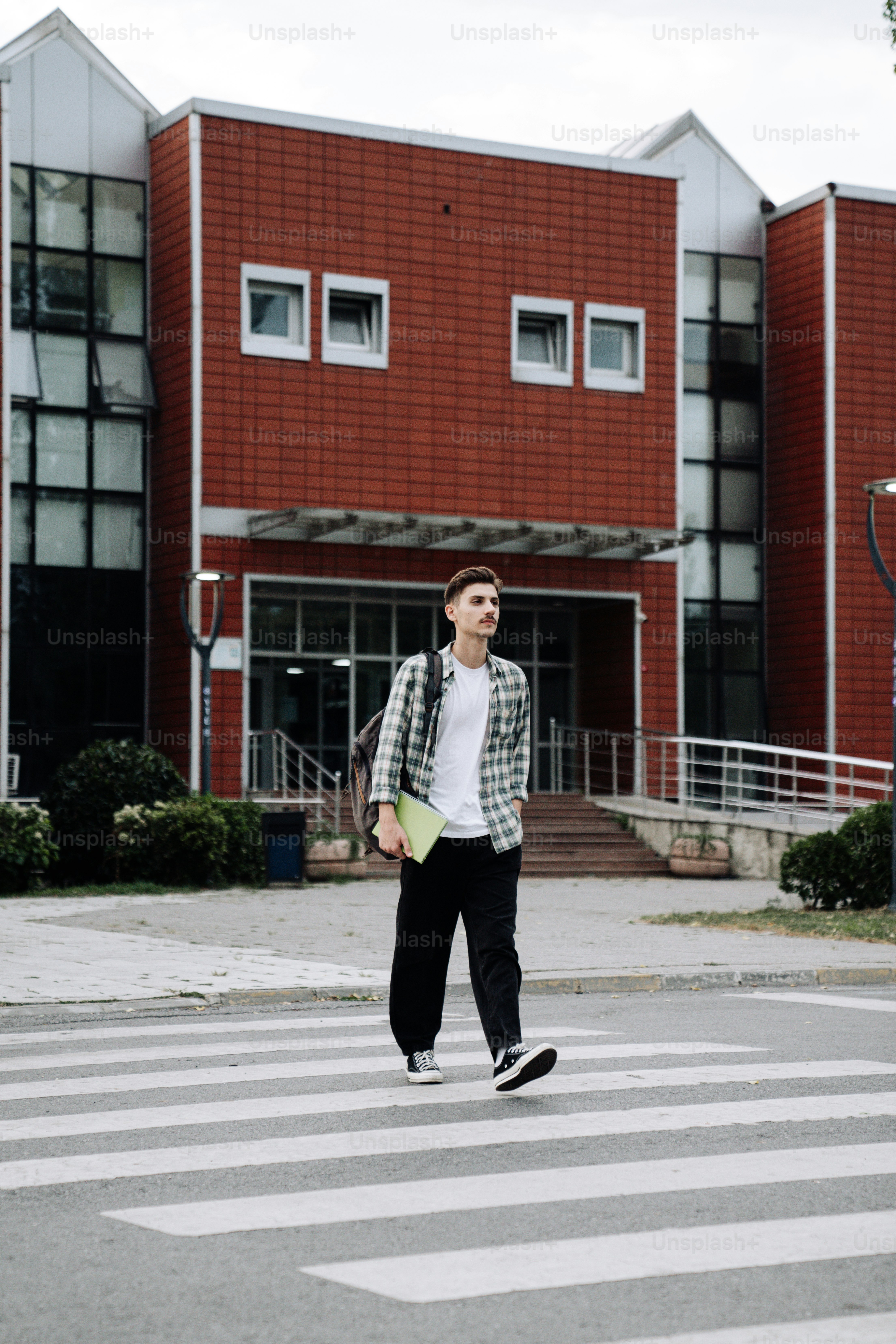 A man walking across a cross walk in front of a building photo ...