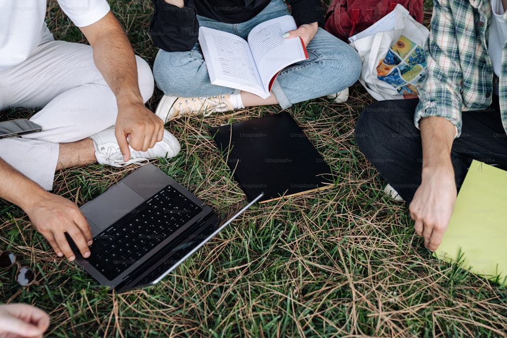 a group of people sitting on the grass with laptops