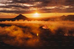 O sol está se pondo sobre uma montanha coberta de nevoeiro