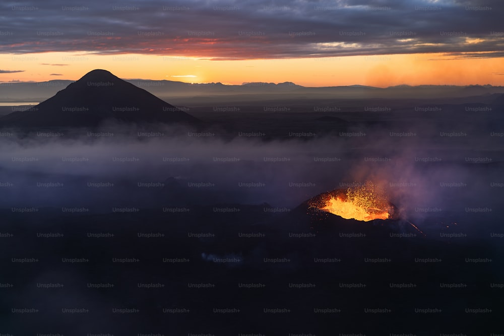Un volcan fait éruption de lave au coucher du soleil