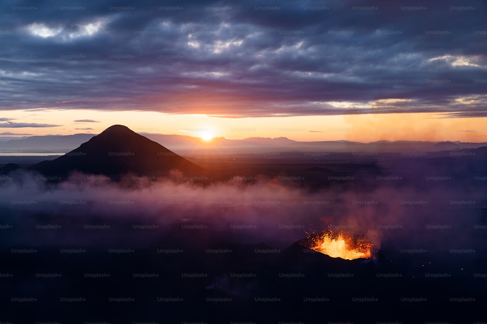 the sun is setting over a mountain with clouds