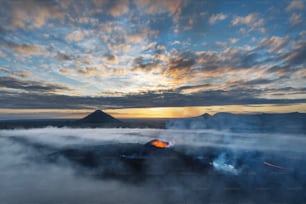 the sun is setting over a mountain covered in clouds