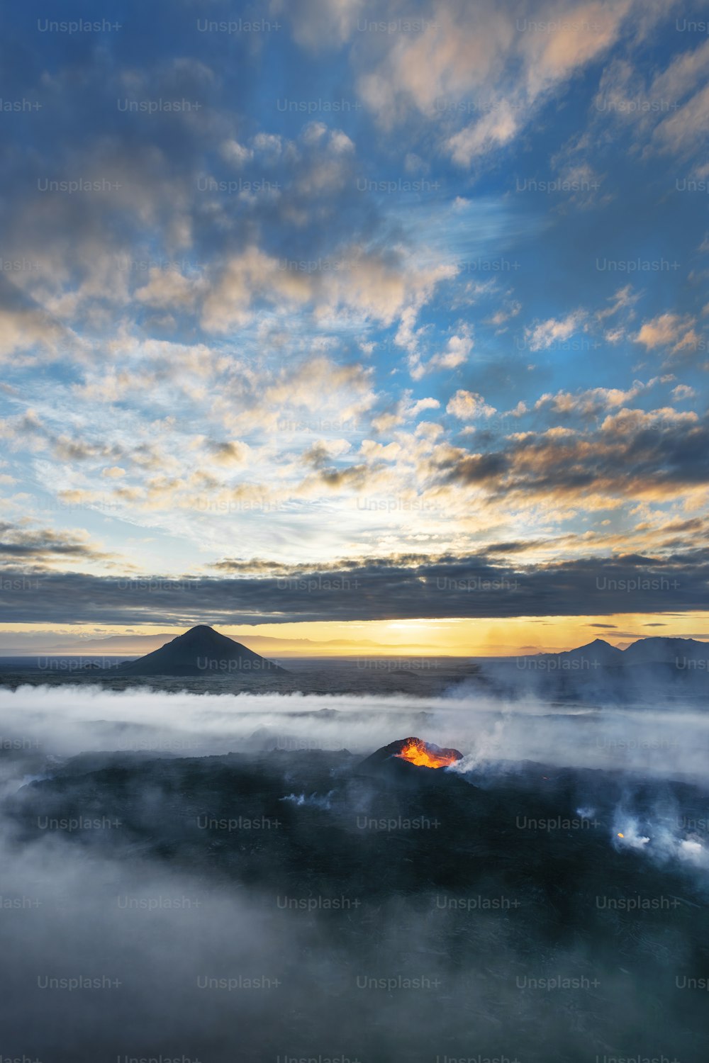 the sun is setting over the mountains and clouds