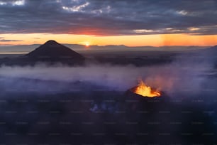 Die Sonne geht über einem Berg mit einem Feuer in der Mitte unter