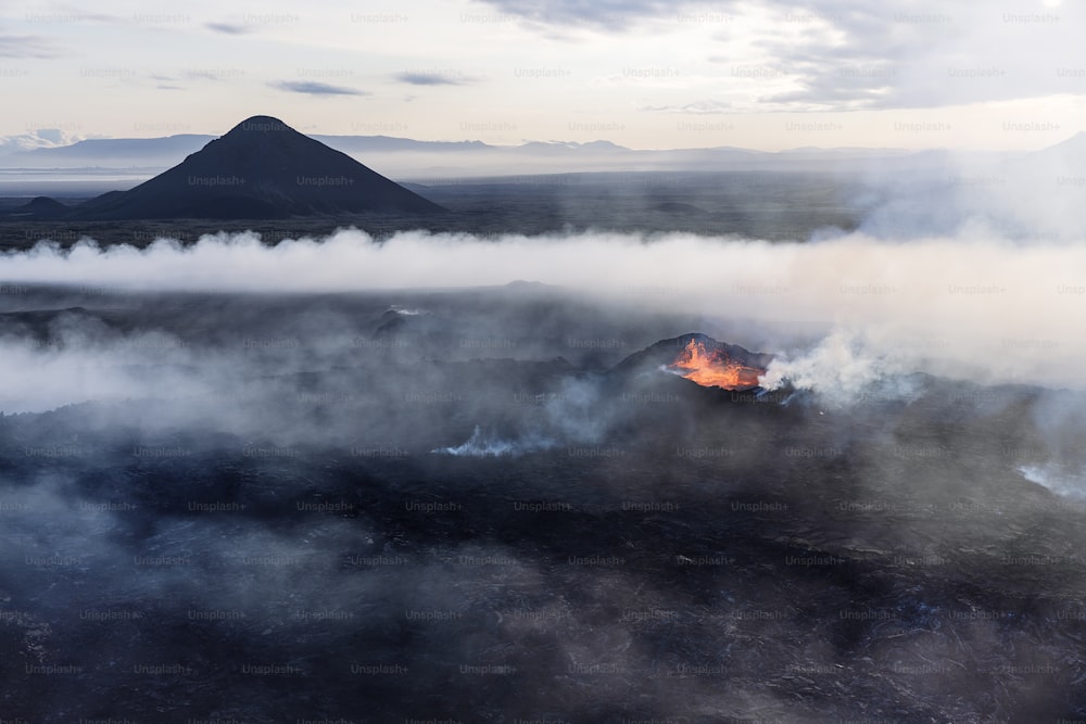 um vulcão expelindo lava no meio de um campo